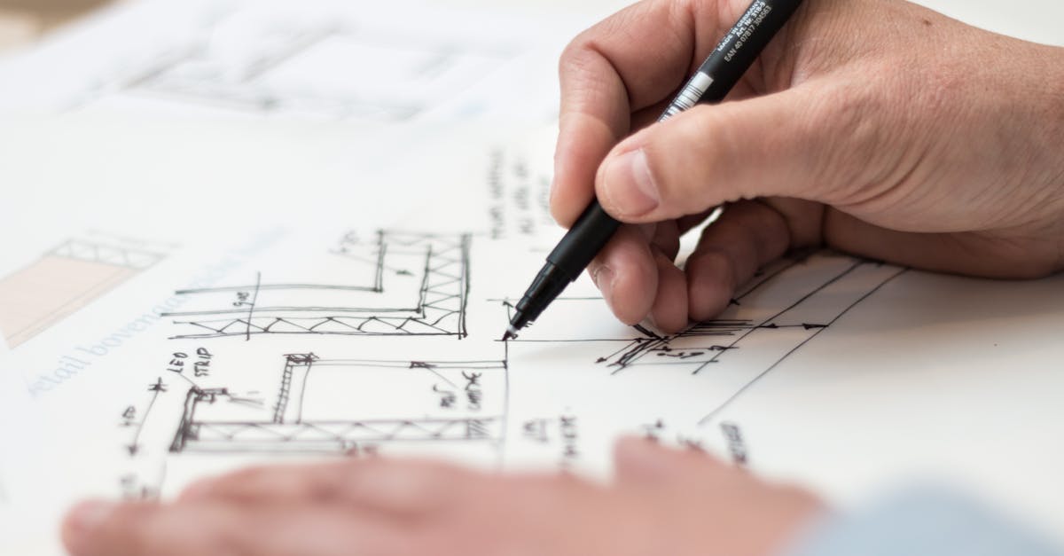 Close-up of hand drawing intricate technical designs on blueprint with pen, ideal for engineering or architecture themes.