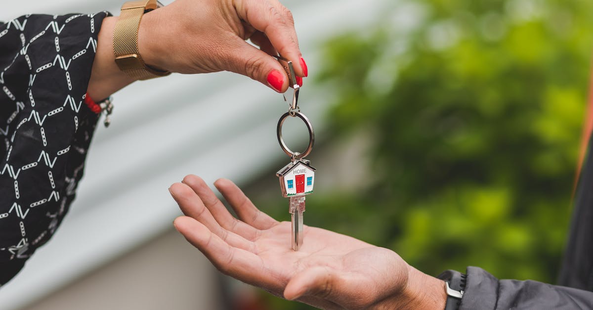 Close-up of a hand handing over a key with a house keychain, symbolizing real estate transaction.