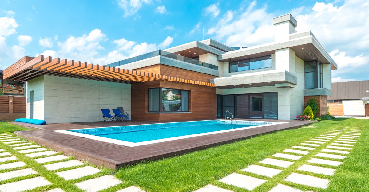 Contemporary house with pool, lush lawn, and clear skies.